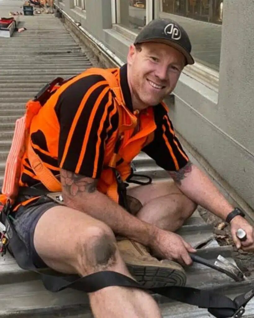 Joniec Plumbing worker smiling, wearing safety gear on site.